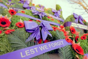 Remembrance Day wreaths with a purple ribbon that reads lest we forget